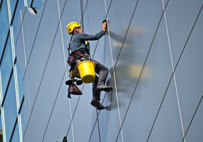 Een glazenwasser hangt hoog aan een kabel.